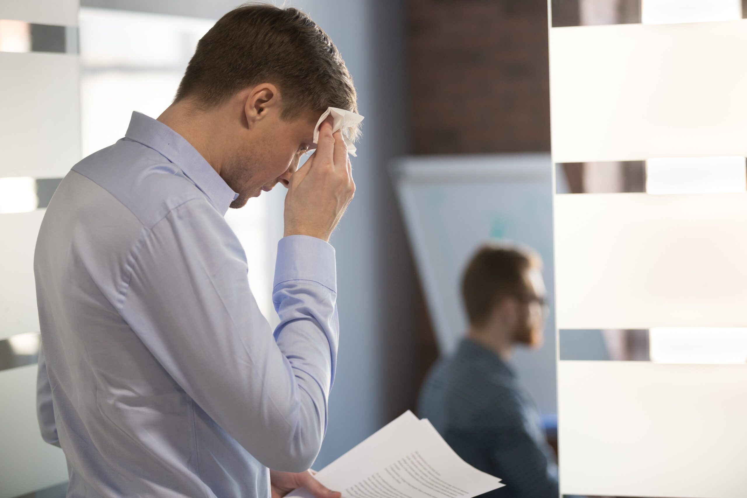 man with public speaking anxiety looking at notes and sweating before speech